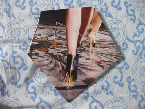 A model's legs and heeled shoes mid-stride, a line of white beaded stitching following the fold