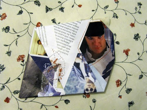 White paper strips folded across a man's capped face, shell and grass fragments caught underneath