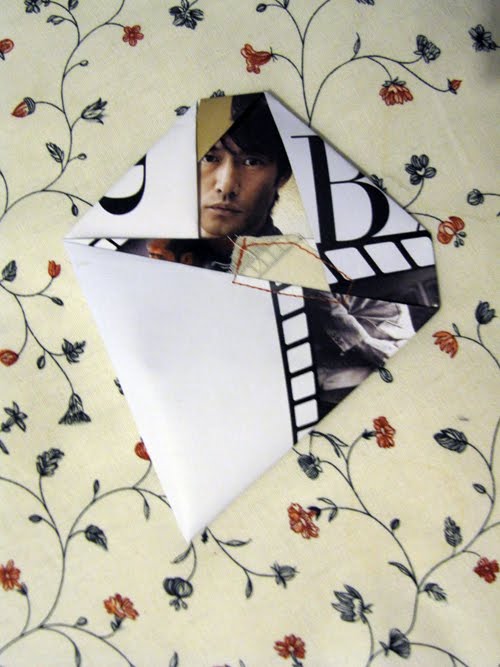 Black and white planes folded around a face, a large letter "B" surfacing at the top edge