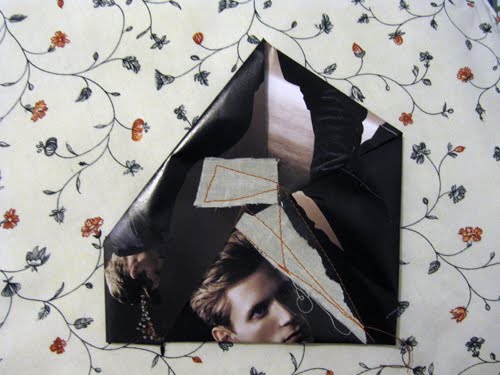 Two faces in a dark fold, small white triangles stitched down across them in pale thread