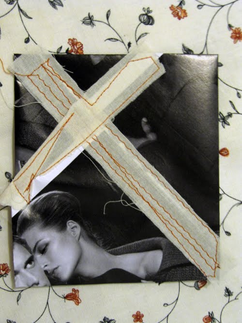 A large orange-stitched cross laid over a woman lying down, her face turned away beneath it